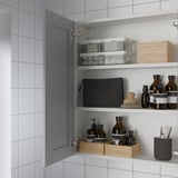 Mueble de baño con espejo, tres estantes y varios artículos de tocador.