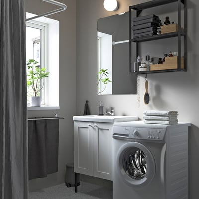 Moderno baño gris con mueble y lavabo blancos ENHET, espejo, lavadora, ventana y planta junto a la ducha.