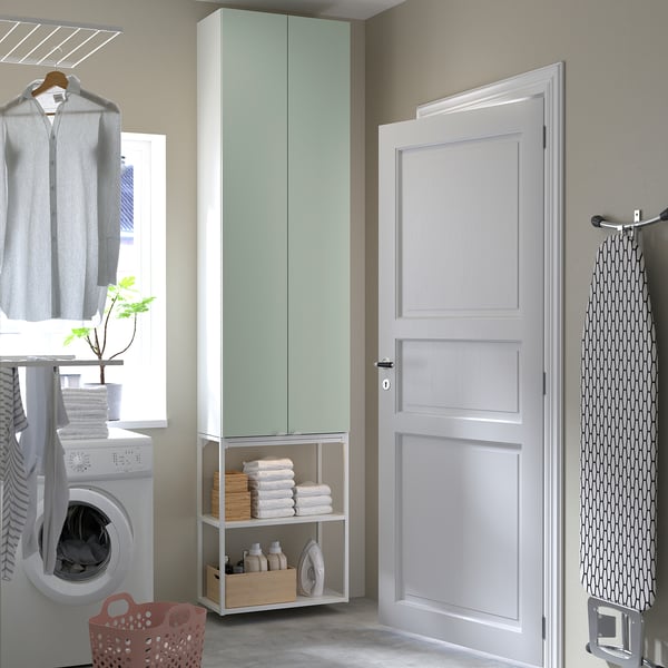 Configuración de lavandería compacta con gabinetes verdes ENHET, canasta roja y secadora.