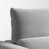 Primer plano del sofá de tela gris. Espalda alta, tejido texturizado, parece suave y de apoyo.