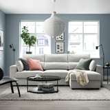 Sofá modular ESKILSTUNA gris, cojines de felpa, respaldos altos, con mesa de centro y alfombra en salón moderno.