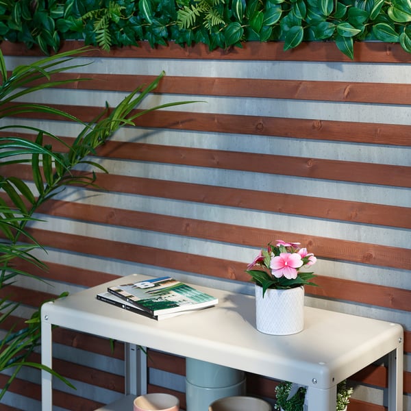 Mesa de exterior con revista y flores rosas contra la pared.