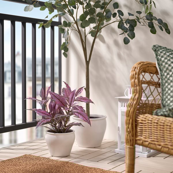 Acogedor balcón con silla de mimbre y planta.