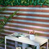 Mesa al aire libre con libros, jarrón y flores junto a la valla de rayas en el balcón.