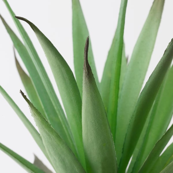 Primer plano de la planta artificial FEJKA, hojas verdes vibrantes, textura detallada.