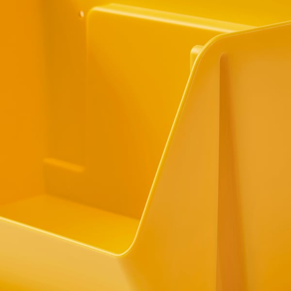 Organizador de almacenamiento de plástico amarillo brillante, bordes suavemente curvados, diseño limpio y moderno, montable en la pared.