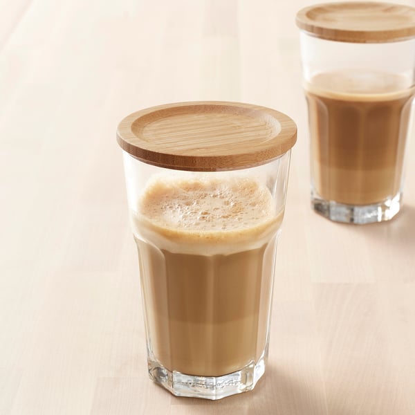 Dos vasos altos con bebidas espumosas y tapas de bambú sobre una superficie de madera clara.