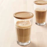 Dos vasos altos con bebidas espumosas y tapas de bambú sobre una superficie de madera clara.