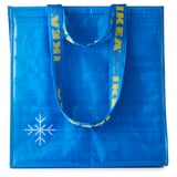 Bolsa de la compra reutilizable azul con asas amarillas y logotipo de copo de nieve blanco. Fabricado a partir de polipropileno y poliéster reciclados.