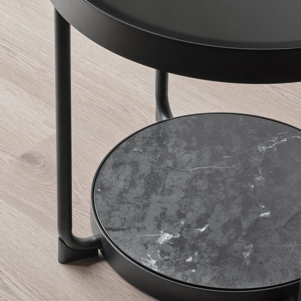 Mesa auxiliar circular negra con estructura metálica robusta y tapa de cristal ahumado, elegante y moderna.