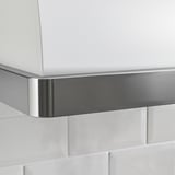 La campana de cocina de acero inoxidable y blanco está montada contra una pared de azulejos blancos. La elegante moldura metálica destaca su diseño moderno.