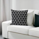 Cojín decorativo con temática de gato sobre sofá blanco.