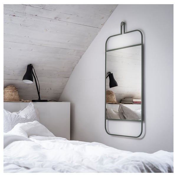 Un dormitorio moderno con un espejo GRANVÅG de pared en color verde. El espejo tiene forma rectangular con un estante para accesorios.