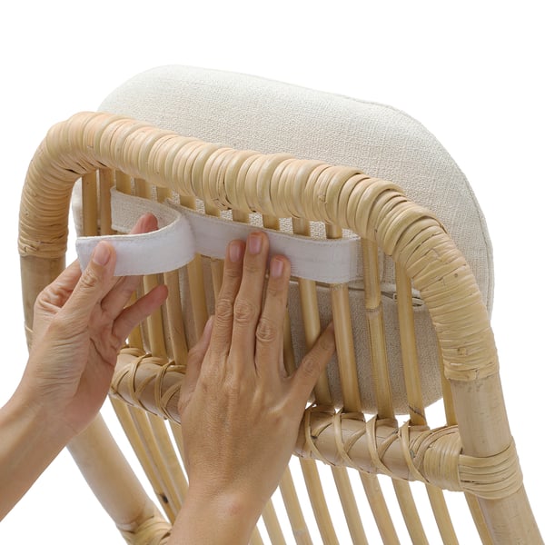 Una persona coloca cojines en una silla de bambú, lo que mejora la comodidad y el apoyo.