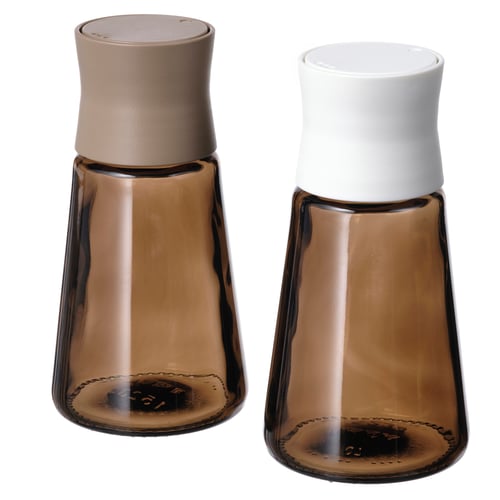 Par de frascos de especias de vidrio marrón con tapas blancas y beige, forma cónica, diseño moderno.