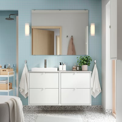 Baño moderno con tocador HAVBÄCK, azulejos azul claro, toallas, planta, espejo, piso estampado, radiador.