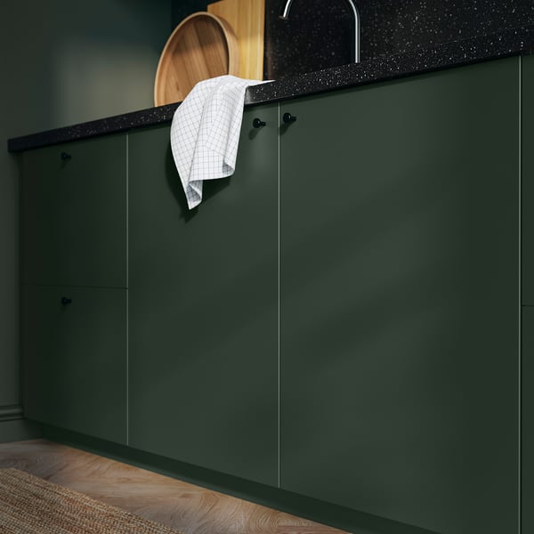 Armarios HAVSTORP de color verde oscuro con encimera negra con una toalla colgada sobre el borde.