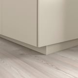 Zócalo de armario de cocina beige que cubre el espacio del suelo, fijándose perfectamente a la base.