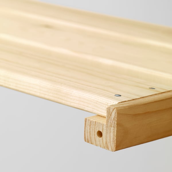Primer plano de una estantería de madera lisa y sin terminar, que muestra su veta fuerte y natural y su ligero bisel en el borde.