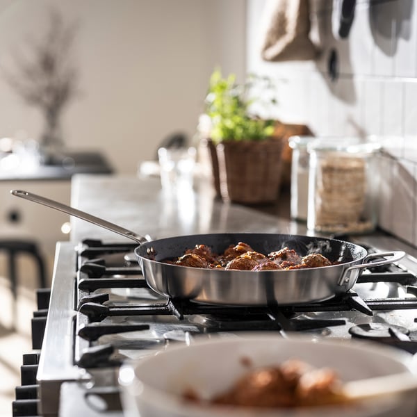 Una sartén cocina los alimentos en una estufa. La superficie antiadherente garantiza una fácil liberación y limpieza de los alimentos.