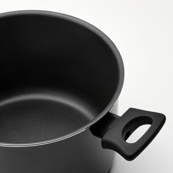 Primer plano del mango y el interior de una olla negra, muestra una superficie antiadherente lisa.