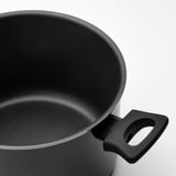 Primer plano del mango y el interior de una olla negra, muestra una superficie antiadherente lisa.