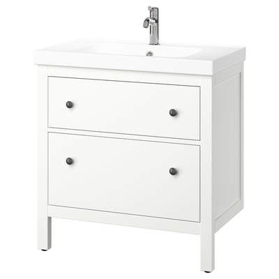 Un tocador de baño blanco HEMNES con dos cajones y un lavabo de cerámica. Tiene pomos negros y un grifo cromado.