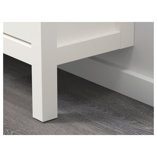 Moderno detalle de base de armario blanco sobre suelo de madera. Muestra un diseño limpio y elegante y una construcción robusta.