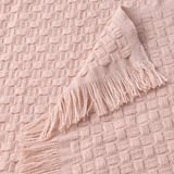 Manta suave de color rosa claro con tejido de cesta texturizado y divertidos flecos, confeccionada en poliéster reciclado.