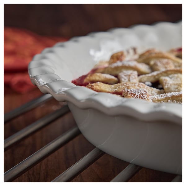 Tarta de manzana en plato de gres, corteza dorada, espolvoreada con azúcar.