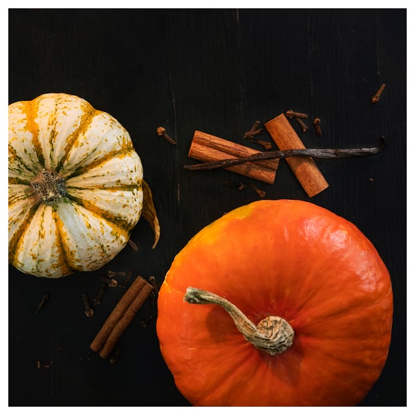 Vela HÖSTAGILLE, naranja, en cristal, aroma otoñal. Diseño de calabaza, fondo oscuro.