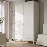 El armario blanco IDANÄS con puertas plegables se encuentra en una habitación. Es elegante y moderno, con suelos de madera clara. Una toalla cuelga de un gancho cerca.