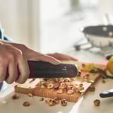 Una persona corta avellanas en una tabla de cortar de madera con un cuchillo.