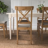 Silla de comedor de madera con asiento acolchado alrededor de una mesa blanca.