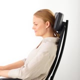 Mujer sentada en silla de oficina ergonómica con soporte lumbar ajustable.