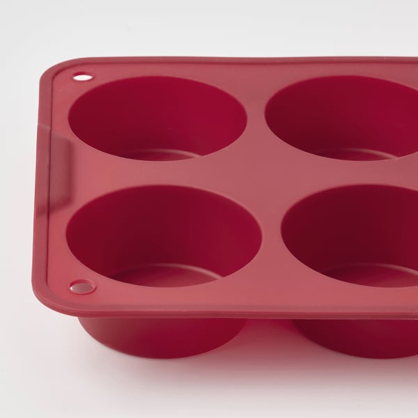 Bandeja para muffins de silicona roja con seis tazas redondas, bordes lisos y dos pequeños orificios en los lados para facilitar su manejo.
