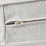 Primer plano del bolsillo del sofá gris texturizado con cremallera, que muestra un tejido de calidad y un diseño duradero.