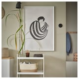 Accesorios en la pared: marco de fotos con arte negro, estante de almacenamiento con cesta y plantas.