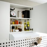 Armario de cocina abierto con varios frascos, botellas y una báscula. Estante ajustable. Salpicadero de lunares negros.