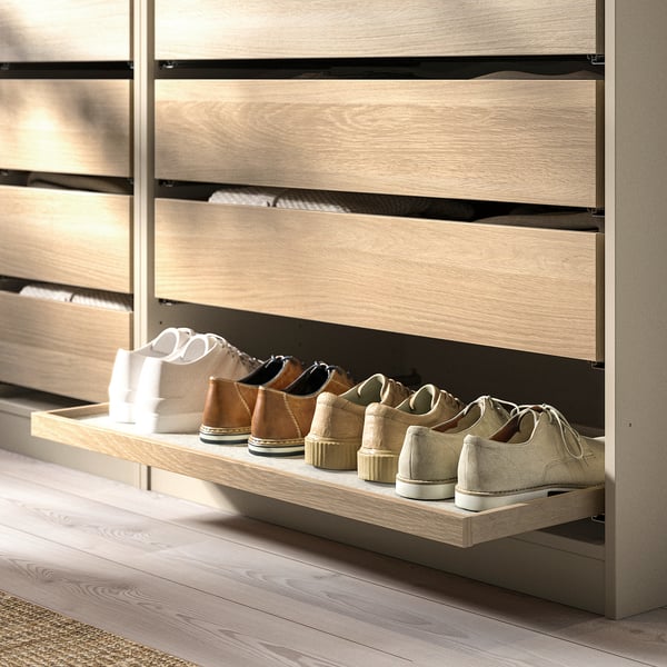 Mueble zapatero de madera con estante extraíble que contiene calzado variado.