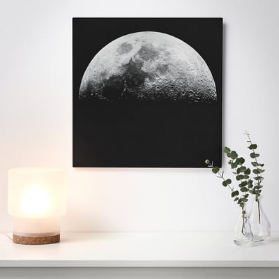 Un arte mural de una media luna sobre un fondo negro, iluminado por una lámpara cercana, dando un efecto 3D.