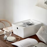 Caja blanca de KUGGIS sobre mesa con fotos y bombilla.