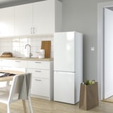 Moderna nevera LAGAN blanca en la cocina, alta con luz led, junto a armarios y sillas.