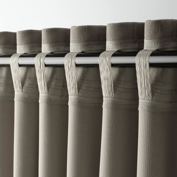 Primer plano de cortinas grises con cabeceras de bolsillo en forma de barra, mostrando su diseño para colgar a través de la barra de cortina.