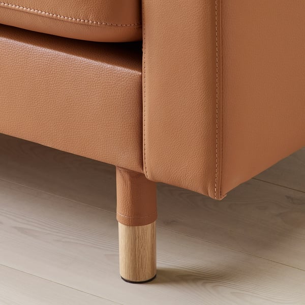 Mueble de cuero marrón con patas de madera. Asiento y respaldo tapizados. Elegante detalle de costuras.
