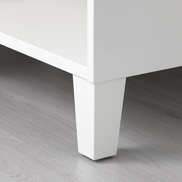 Primer plano de la pata de un mueble blanco con un diseño limpio y elegante, montado sobre suelo de madera, con un acabado de alta calidad.