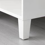Primer plano de la pata de un mueble blanco con un diseño limpio y elegante, montado sobre suelo de madera, con un acabado de alta calidad.
