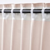 Primer plano de la cortina: rosa claro con motas oscuras, bolsillo de varilla en la parte superior, lengüetas para colgar.