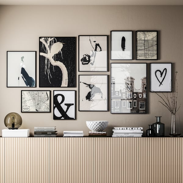 Galería en blanco y negro con arte, libros, lámpara y jarrones.
