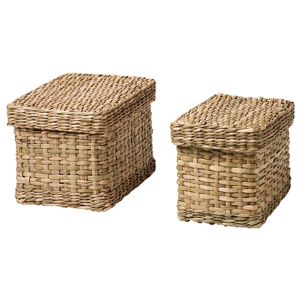 Dos cestas de almacenamiento de pastos marinos tejidas a mano. Uno es más grande, el otro más pequeño, ambos rectangulares con tapa. El color y la textura naturales le dan un aspecto rústico.